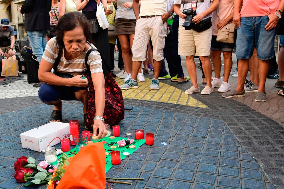 A woman displays a candle next to first flowers and a message to the victims on August 18, 2017 on the spot where yesterday a van ploughed into the crowd, killing 13 persons and injuring over 100 on the Rambla boulevard in Barcelona. Photo: JAVIER SORIANO/AFP/Getty Images