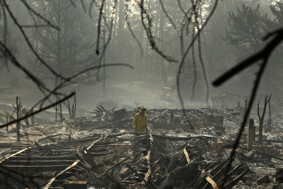 A firefighter searches for human remains in a trailer park (John Locher/AP)