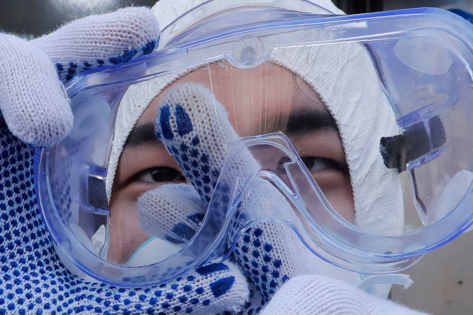Preventative action: A worker cleans his goggles to spray disinfectant at a shopping street in Seoul, South Korea. Photo: AP