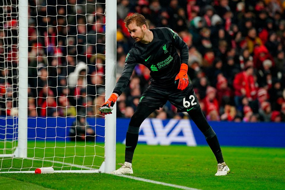 El portero de Liverpool, Caoimhin Kelleher, retira un pastel arrojado del campo durante el partido de cuartos de final de la Copa Carabao en Anfield, Liverpool.