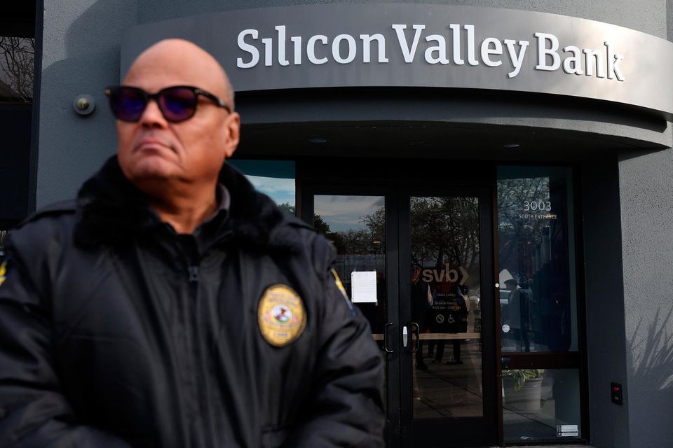 Real-life effects: A security guard monitors a line of people outside a Silicon Valley Bank in Santa Clara, California as customers line up to try to retrieve their funds from the failed bank. Photo: Getty