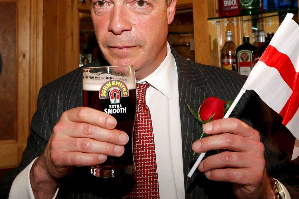 Sign of Britain's uneasy gut: Ukip leader Nigel Farage holds a flag bearing a St George’s Cross as he enjoys a pint of beer on St George’s day