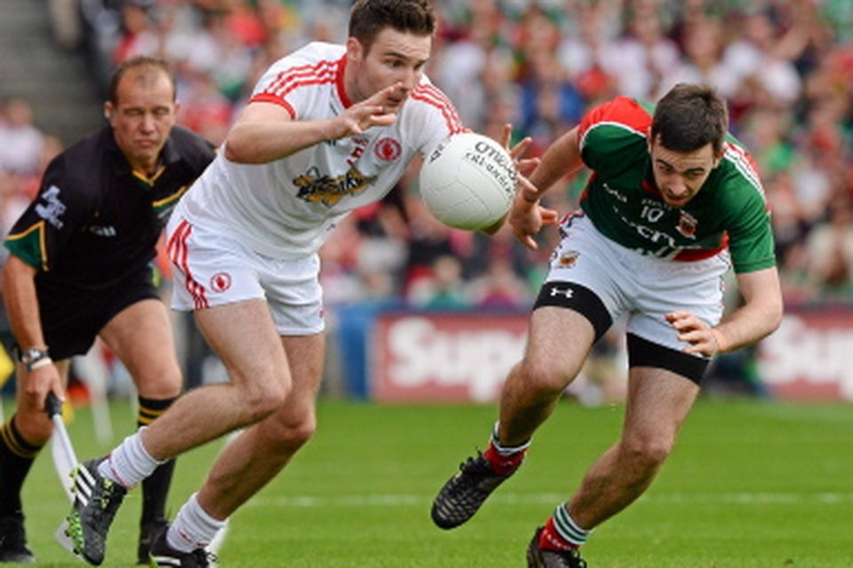 Tyrone's Ciarán McGinley rushes past Kevin McLoughlin on his way to score the first point of the game