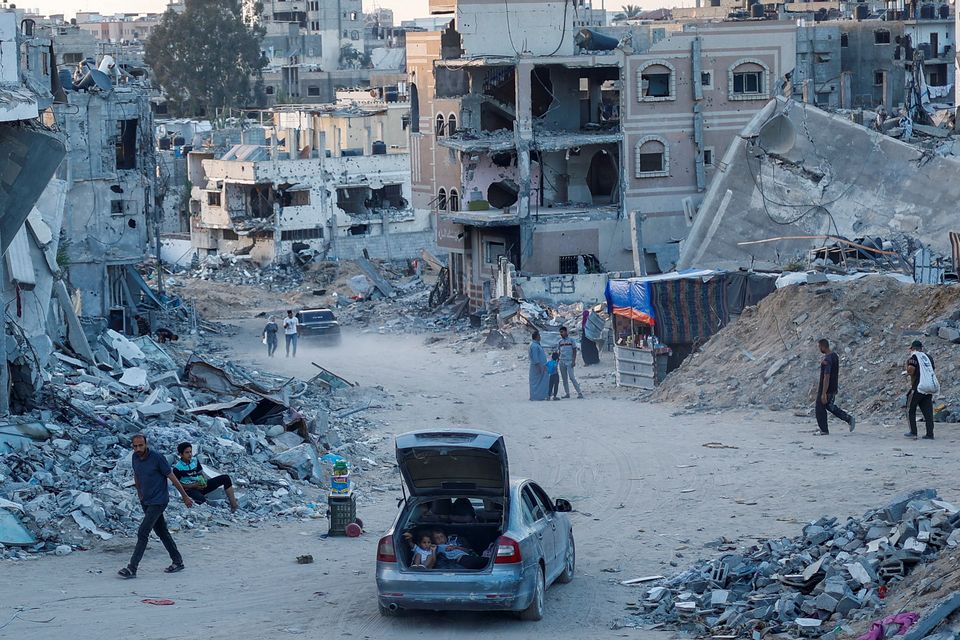 Children sit in the boot of a car as Palestinians walk amid the rubble of houses and shops destroyed in an Israeli strike yesterday in Khan Younis in the southern Gaza Strip. Photo: Reuters