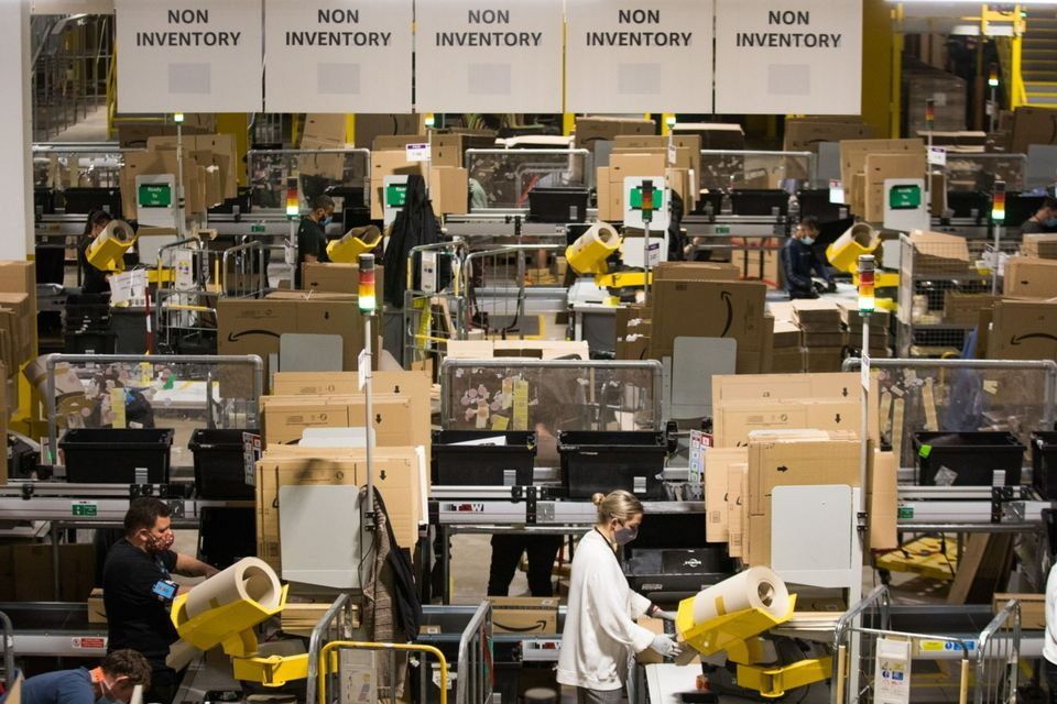 “Currently in Ireland delivery takes four or five days from many websites.  But in the UK it usually takes two or three days at most.  Above, the Amazon warehouse in Kegworth, UK.  Photo: Chris Ratcliffe/Bloomberg