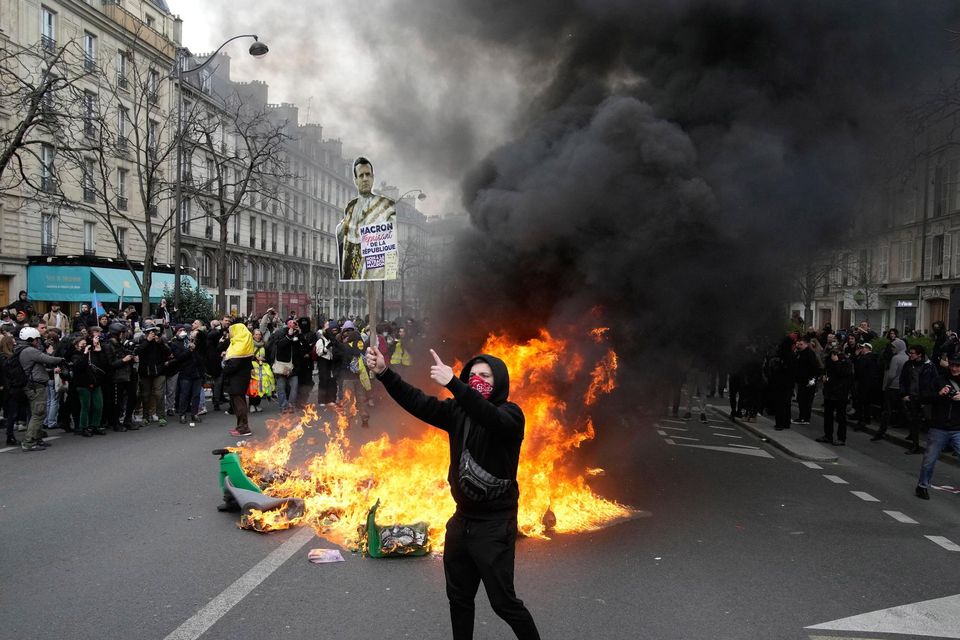 A demonstrator holds up a poster mocking French president Emmanuel Macron in Paris. Photo: Christophe Ena/AP