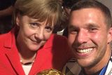thumbnail: Lukas Podolski and Angela Merkel pose with the World Cup trophy