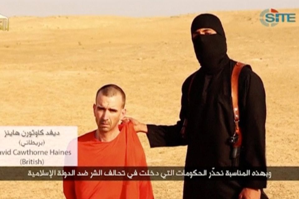 A masked, black-clad militant, who has been identified by the Washington Post newspaper as a Briton named Mohammed Emwazi, stands next to a man purported to be David Haines in this still image from a video obtained from SITE Intel Group website February 26, 2015