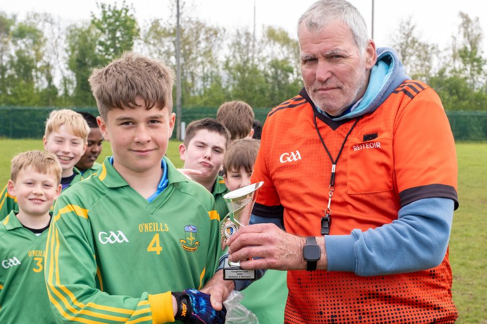 Kilcoole captain Mason Kelly receives the Divison 3 cup from referee Philip Bracken at the Wicklow Cumann Na mBunscol Coughlan Cup competition at Bray Emmets.