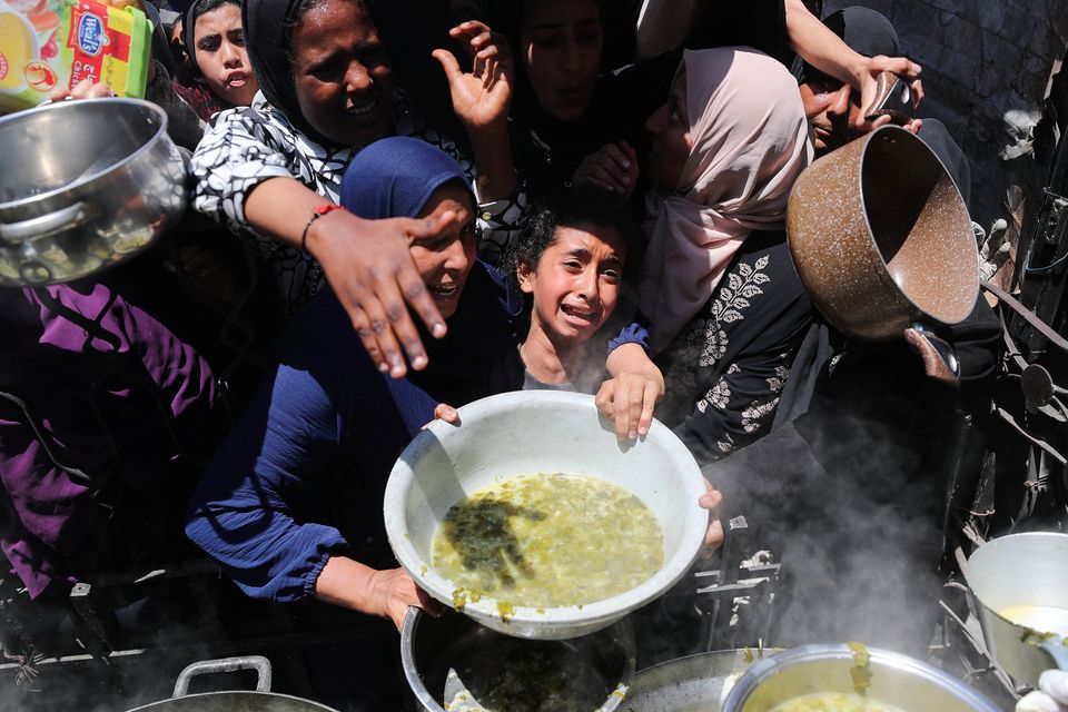 A girl reacts as Palestinians wait to receive food cooked by a charity kitchen, in Beit Lahia, northern Gaza Strip, on Thursday. Photo: Mahmoud Issa/Reuters