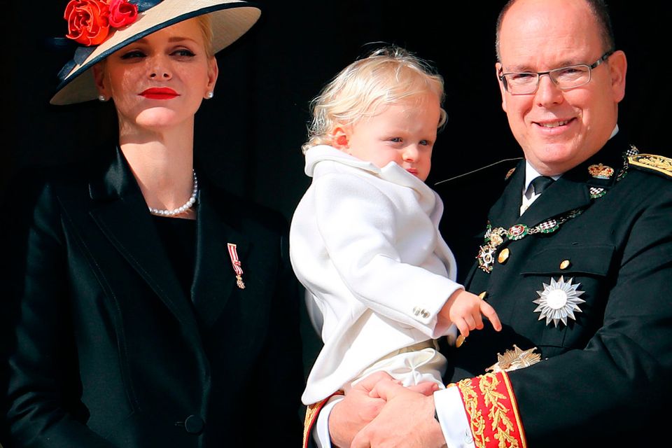 Prince Albert II of Monaco (R) holding Prince Jacques, and princess Charlene of Monaco (L) appear on the balcony of the Monaco Palace