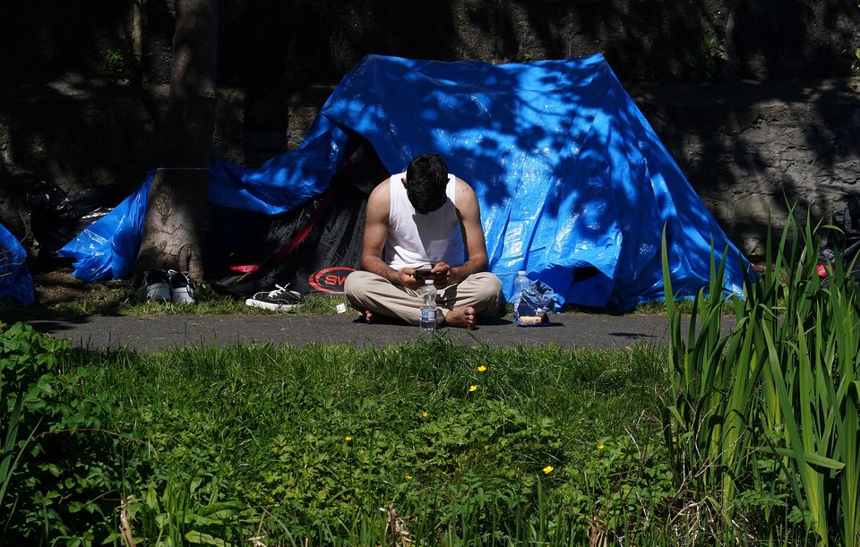 A man sits outside one of the dozens of tents (Brian Lawless/PA)