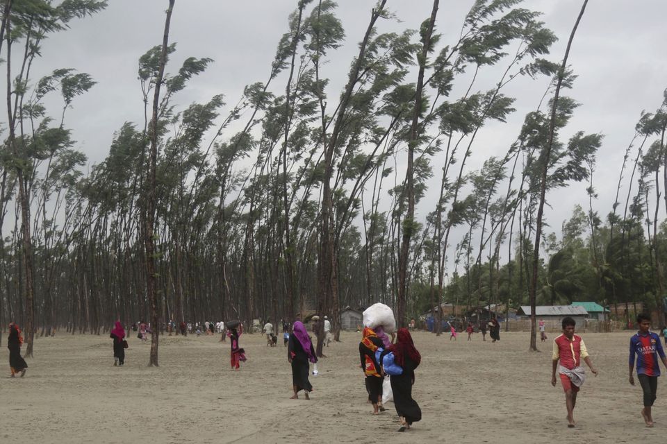 Bangladeshis carry their belongings and walk home after spending a night at a shelter in Cox's Bazar (AP)