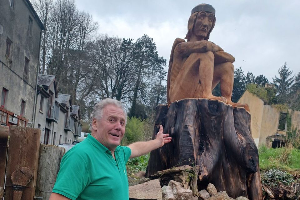 Mullichain cafe and restaurant co-owner, Martin O'Brien with the 'Mad Sweeney' wooden sculpture outside the premises in St Mullins, Co Carlow. 