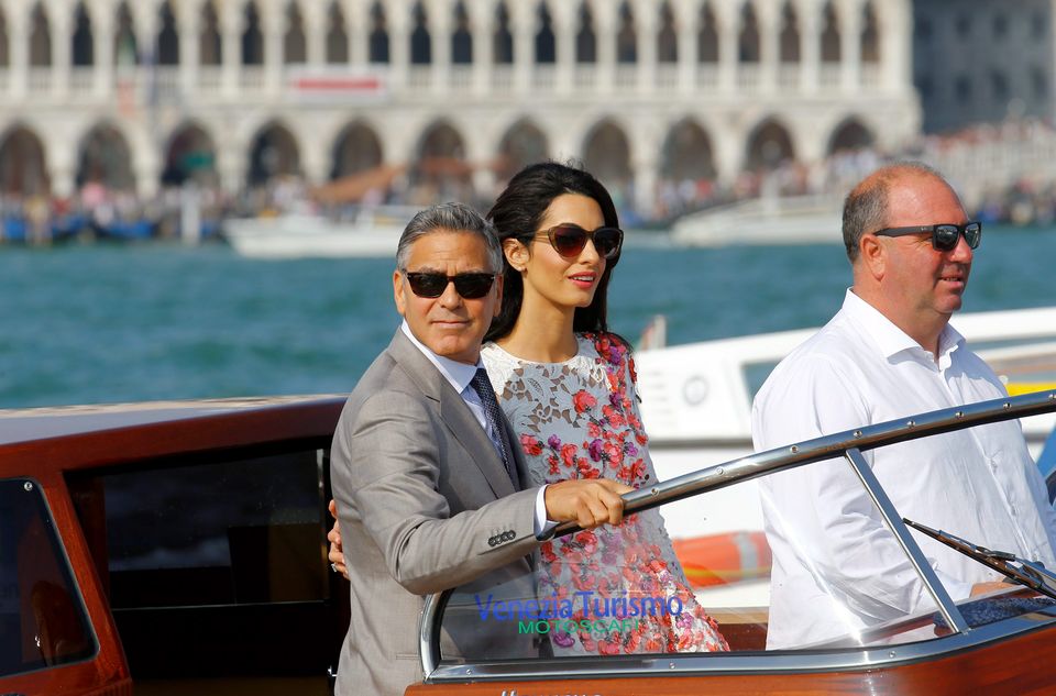 U.S. actor George Clooney and his wife Amal Alamuddin stand on a water taxi at the Grand Canal in Venice