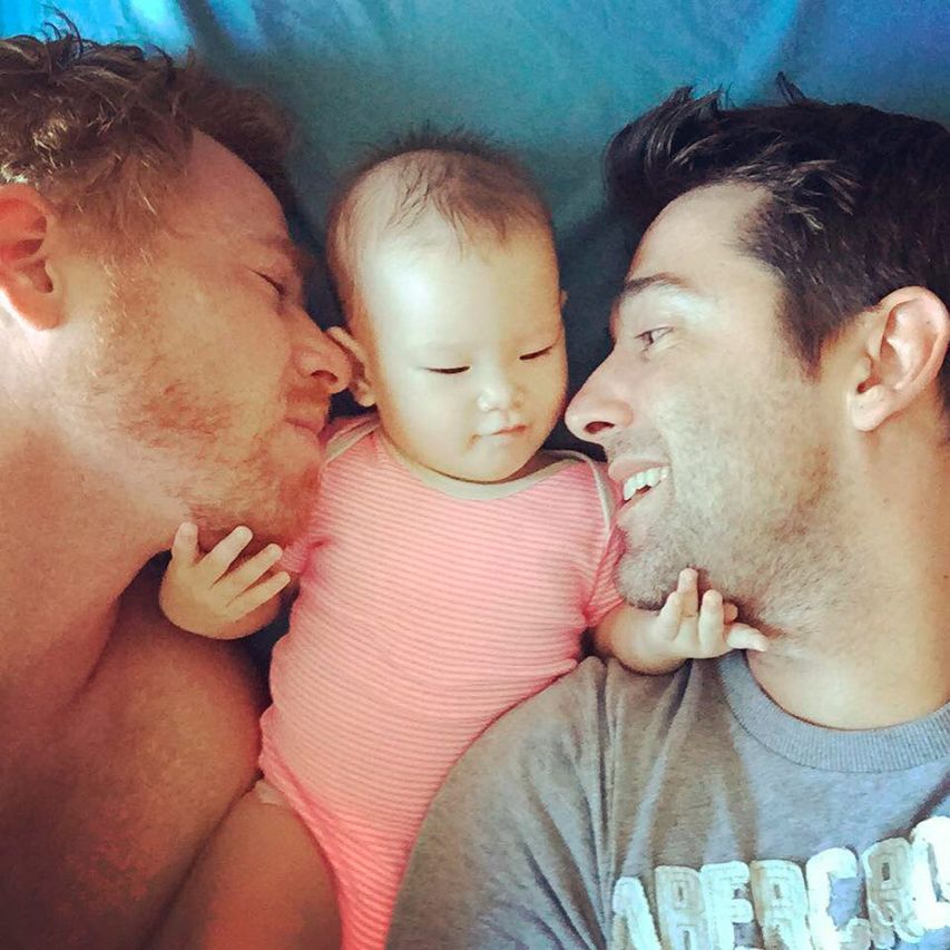 Gay couple sharing sweet moments with a surrogate mom. The young  fathers-to-be putting their