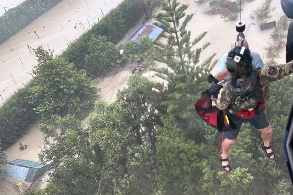 A person is winched from a rooftop of a home to safety by helicopter in the Esk Valley, near Napier, New Zealand. (New Zealand Defense Force via AP)