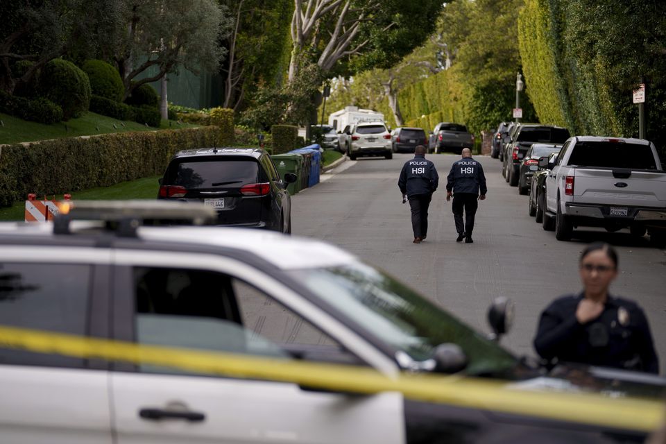 Authorities walk on a street near a property belonging to Sean ‘Diddy’ Combs (Eric Thayer/AP)