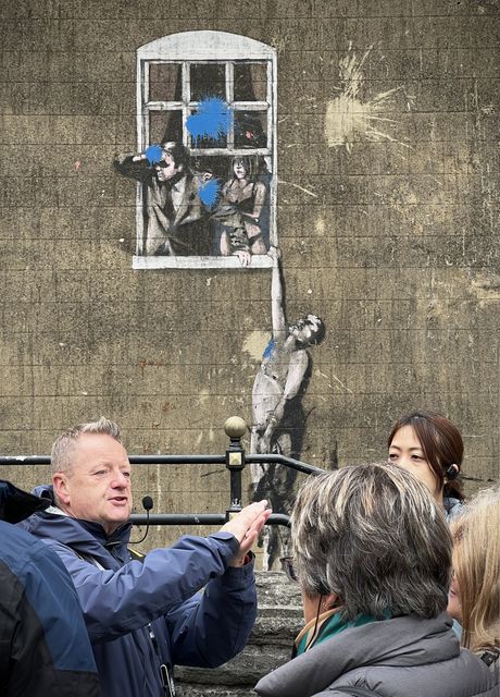 John Nation of Where the Wall tours talks next to Banksy's Well Hung Lover