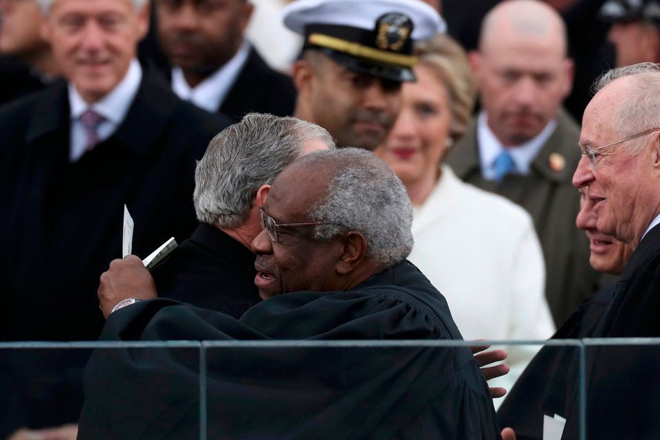 Former U.S. President Bill Clinton (L) looks on as former U.S. President George W. Bush hugs justice Clarence Thomas (R) as they attend the presidential inauguration of President-elect Donald Trump at the U.S. Capitol in Washington, U.S., January 20, 2017. REUTERS/Carlos Barria