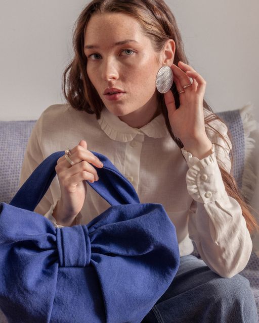 August Night cobalt blue cotton mini bow bag, €255, with linen blouse from Jennifer Slattery and earrings by Daki Daki Jewellery. Photo: Mark Hill.