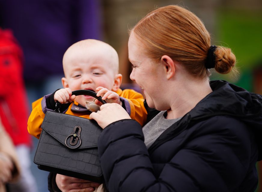 Lucy Williams holds Daniel as he plays with the handbag (Ben Birchall/PA)