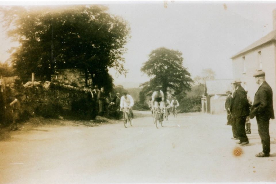 A bicycle race passing through the square in old Ballinalea in the 1940s towards Glenealy, with Terry Macs pub to the right, now known as the Woodpecker.
