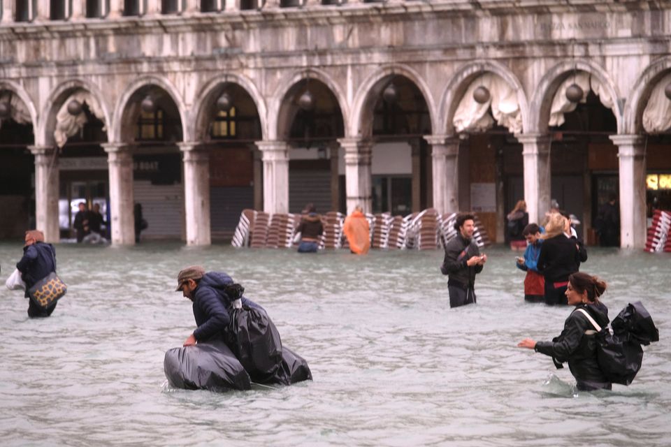 People walk in a flooded Saint Mark Square during a period of seasonal high water in Venice, Italy October 29, 2018 Reuters/Manuel Silvestri