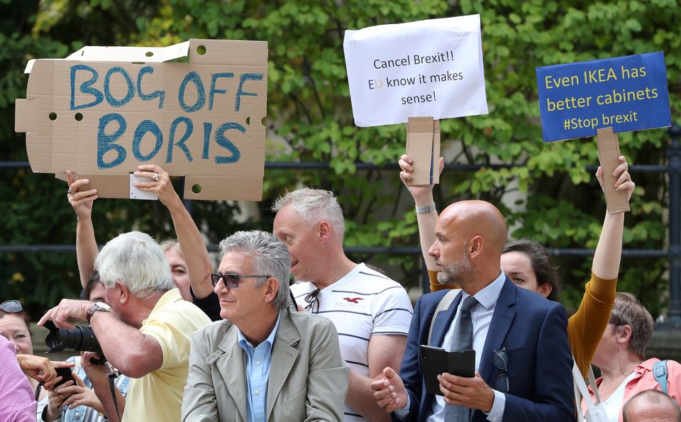 People hold placards as they protest outside a restaurant where British Prime Minister Boris Johnson meets with European Commission President Jean-Claude Juncker in Luxembourg. Picture: REUTERS/Yves Herman