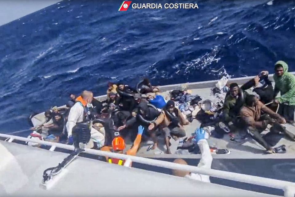 In this image taken from a video released by the Italian Coast Guard, a boat with migrants is approached by a rescue operation off the island of Lampedusa in the Mediterranean Sea (Guardia Costiera/AP)