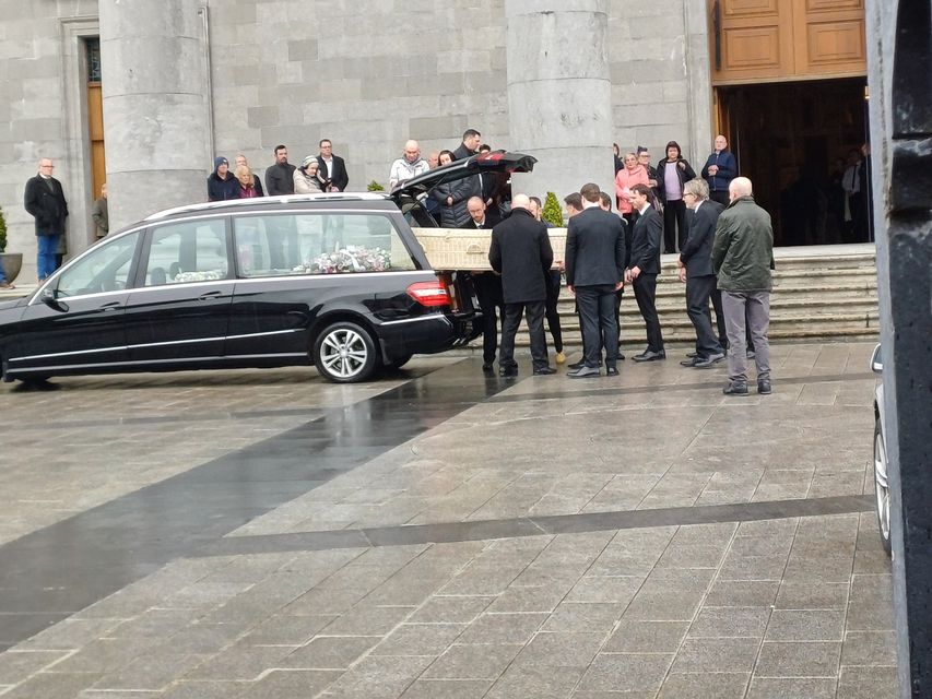 The remains of the late Sarah McNally are carefully taken from a hearse outside St Mel's Cathedral as mourners watch on.