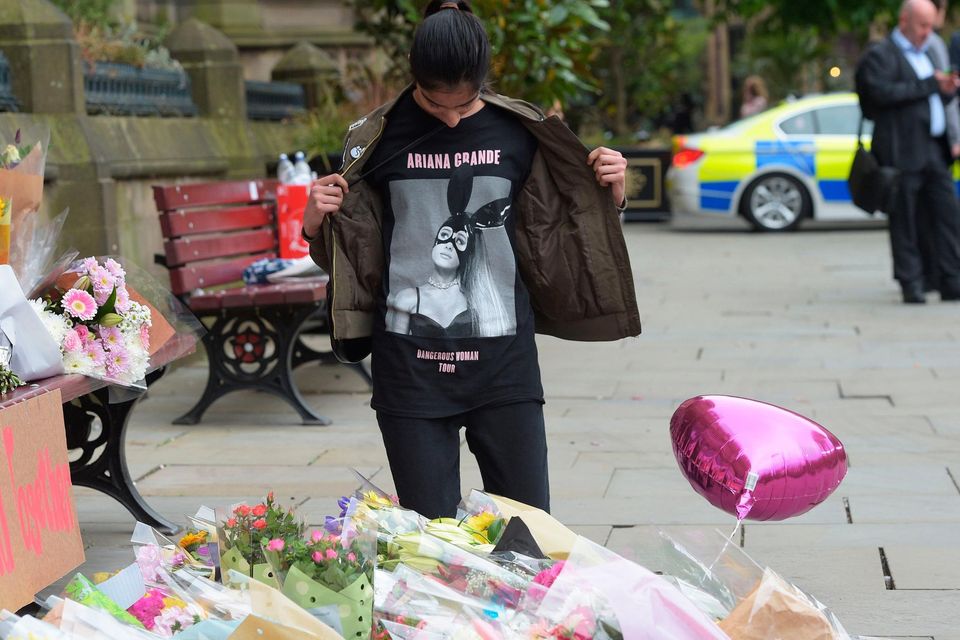 A girl in an Ariana Grande T-shirt looks at flowers outside Manchester Town Hall after a suicide bomber killed 22 people leaving a pop concert at Manchester Arena in 2017. Photo: PA