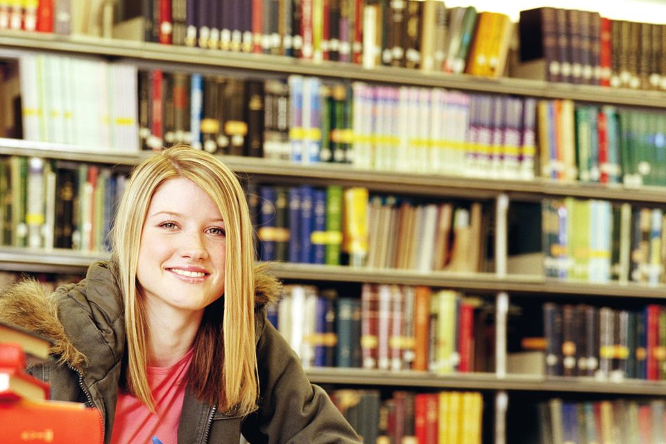 Female college student in library, smiling, portrait