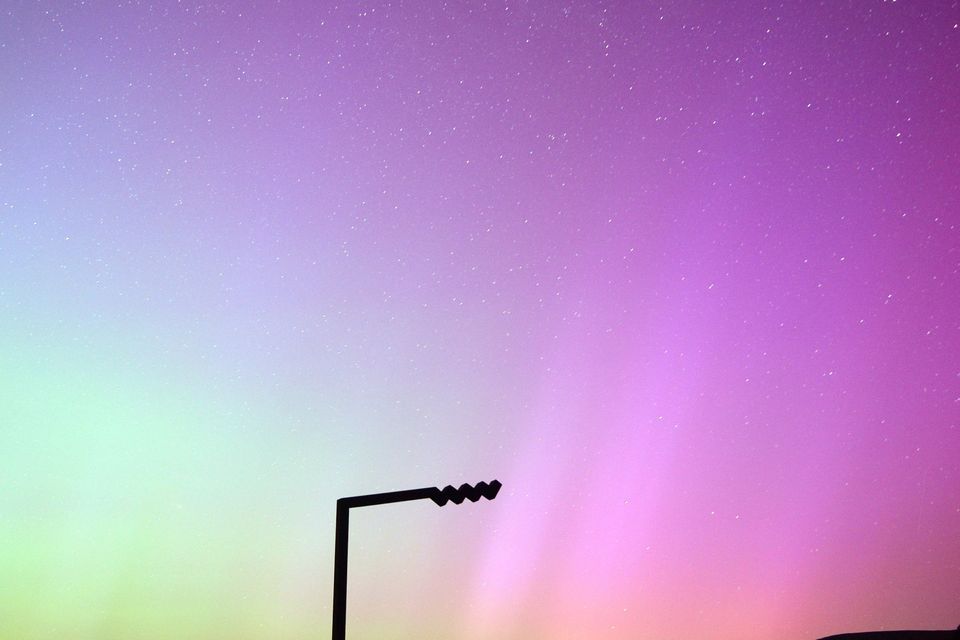 La aurora boreal sobre la bahía de Tralee vista desde la cima de Conor Pass a las 2 a. m. del sábado por la mañana.  A simple vista se ve un tenue resplandor en el cielo, pero la cámara revela todo el espectro de colores producidos por la tormenta solar.  Foto de Declan Malone.