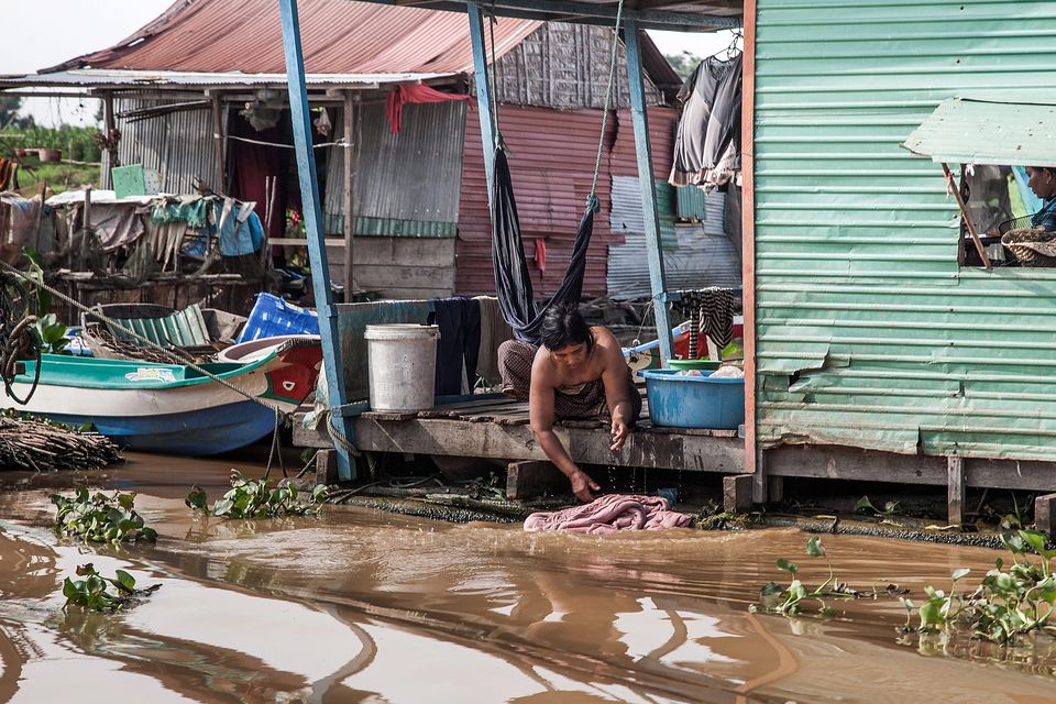 A woman washes her clothes in the water of the Tonle Sap Lake in her home
