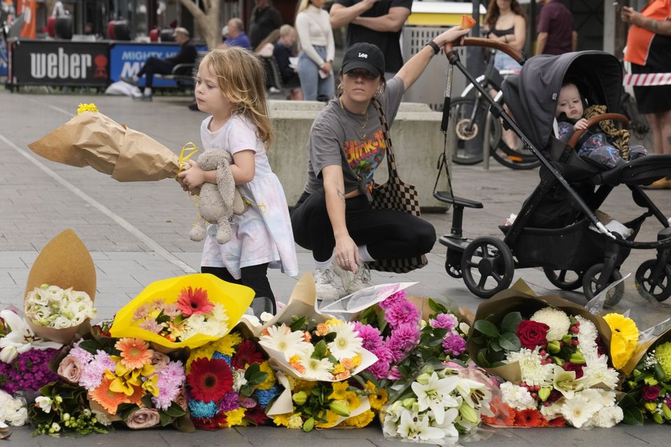 A young child carries flowers to place as a tribute near the crime scene at Bondi Junction, Sydney, where the stabbings took place. Photo: Rick Rycroft